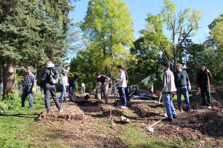 十大赌博靠谱网站平台 students rake mulch in an area park.